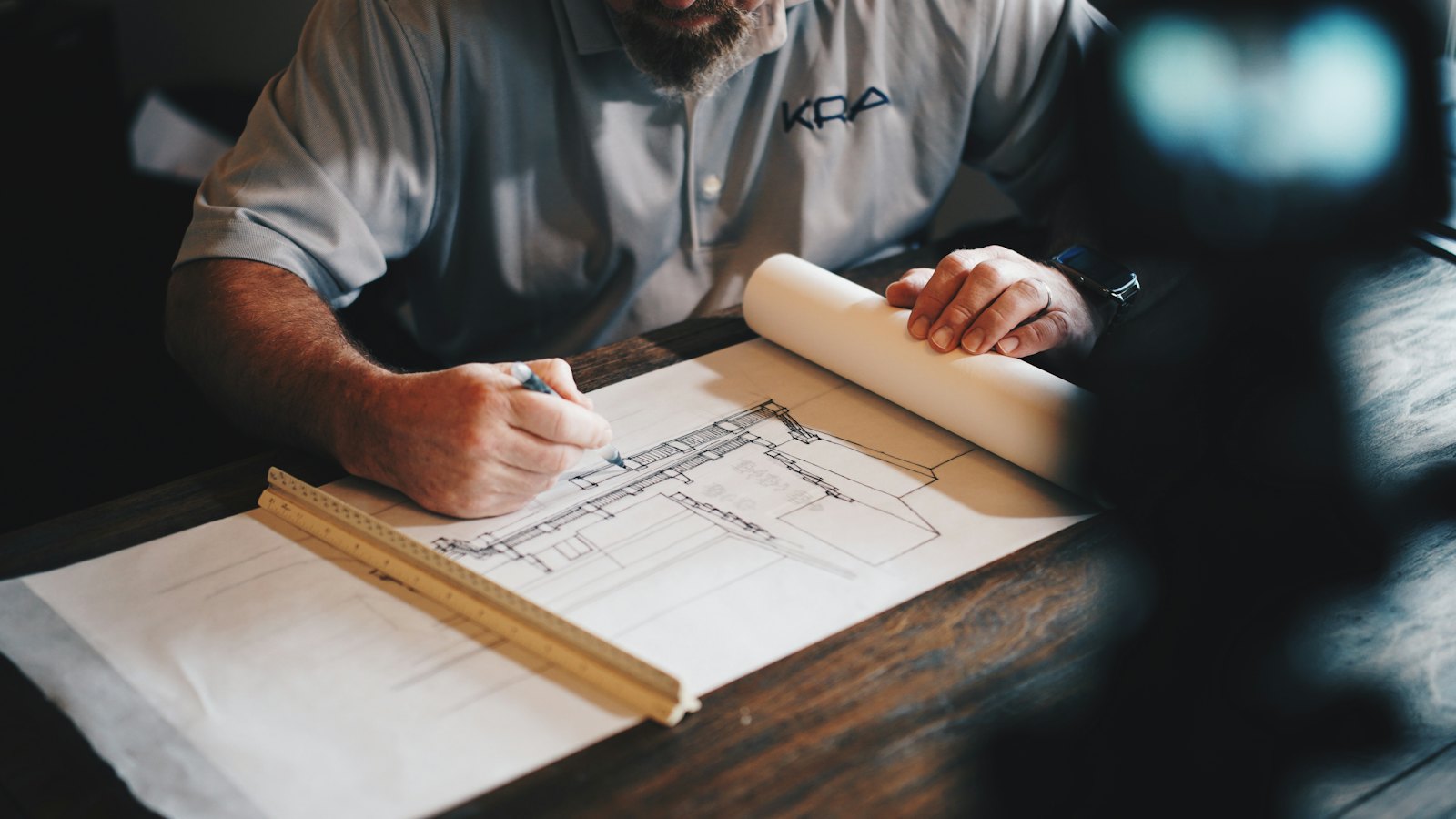 Ingeniero dibujando sobre un plano con lápiz y regla